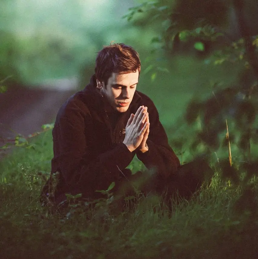 Hombre meditando en medio de un bosque verde