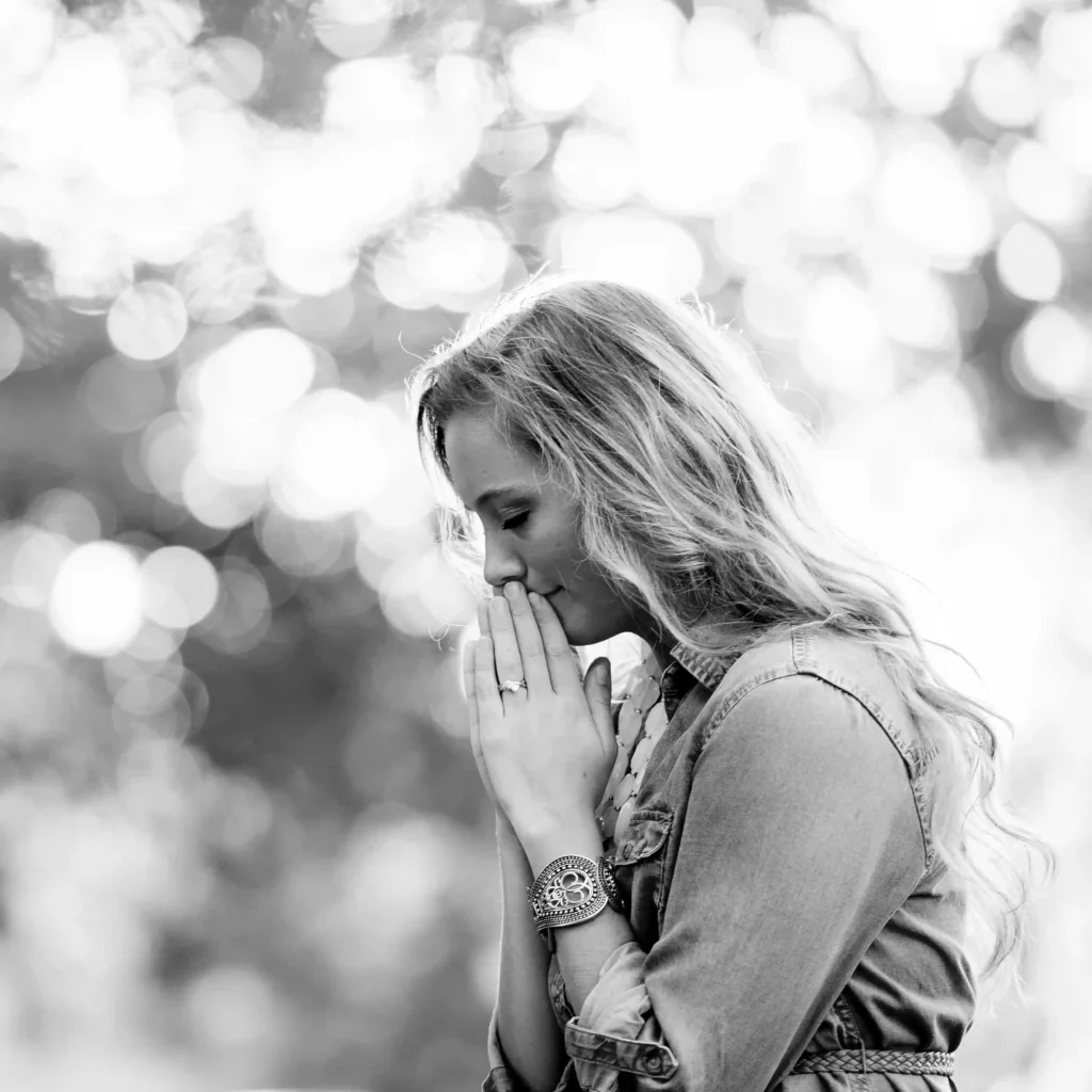Foto en blanco y negro de una mujer rezando en un bosque.